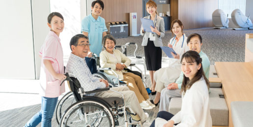 介護施設のスタッフと入居者が共用スペースで集合写真を撮っている様子